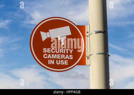 Orange videocamera di sicurezza in uso Segno su grigio Post e Parzialmente soleggiato Background II Foto Stock