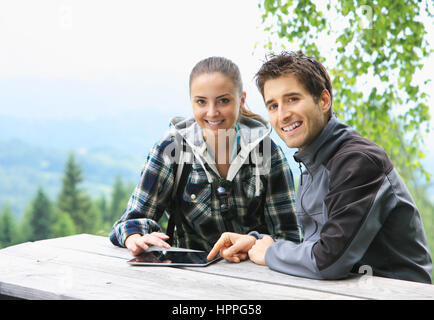 Coppia sorridente utilizzando tablet sulla montagna Foto Stock