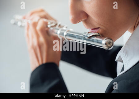 Professional elegante flautista femmina di eseguire in una camera bianca, mani vicino fino Foto Stock