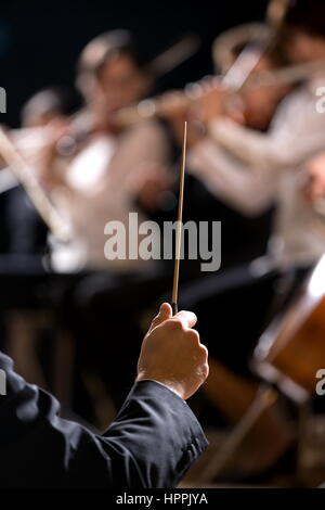 Il conduttore dirigere Symphony orchestra con esecutori su sfondo, mani di close-up. Foto Stock