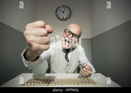 Vintage lavoratore di ufficio arrabbiato e a urlare contro il computer. Foto Stock