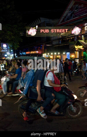 Strada trafficata scena in Siem Reap, Cambogia, guardando verso il basso "Pub Street' con i ciclomotori, la gente del posto e turisti e tuk tuks. Foto Stock