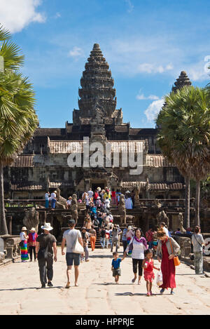 La folla e i gruppi di turisti a piedi o di lasciare l'ingresso principale di Angkor Wat (west gate). Foto Stock