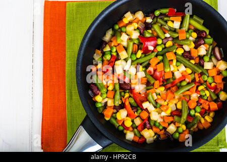 Cibo vegetariano: verdure in padella su bianco sullo sfondo di legno. Foto Studio Foto Stock