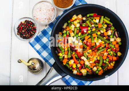 Cibo vegetariano: verdure in padella su bianco sullo sfondo di legno. Foto Studio Foto Stock