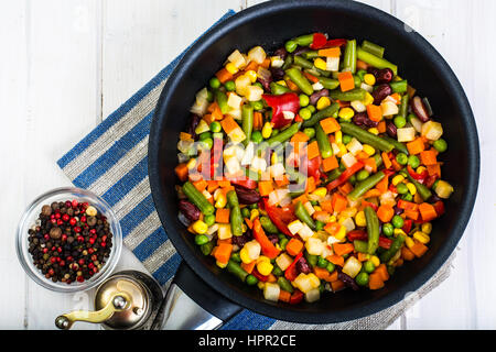 Cibo vegetariano: verdure in padella su bianco sullo sfondo di legno. Foto Studio Foto Stock