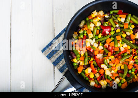 Cibo vegetariano: verdure in padella su bianco sullo sfondo di legno. Foto Studio Foto Stock