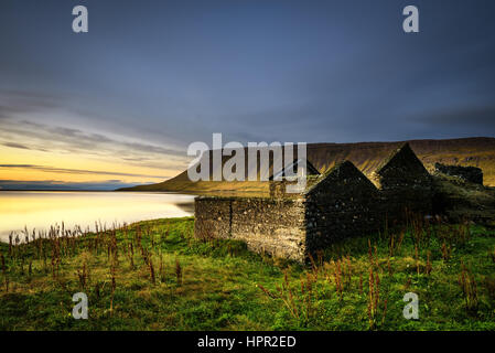 Paesaggio panoramico incluso casa in rovina, tipiche scogliere e un lago in Islanda. Lunga esposizione. Foto Stock