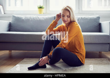 Ritratto di donna attraente seduto sul tappeto in salotto Foto Stock