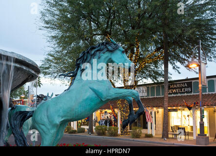 Fontana con bronzo Arabian Horse sculture e negozi sulla Quinta Avenue a Scottsdale, Arizona, al tramonto. Foto Stock