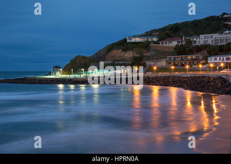 Dunedin, Otago, Nuova Zelanda. Vista lungo gli illuminati spianata per Forbury Hill al crepuscolo, St Clair, lo storico Hot piscina di acqua salata prominente. Foto Stock