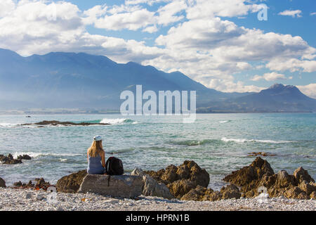 Kaikoura, Canterbury, Nuova Zelanda. Vista sulla baia di Kaikoura Seaward gamma, giovane donna che guarda al mare. Foto Stock