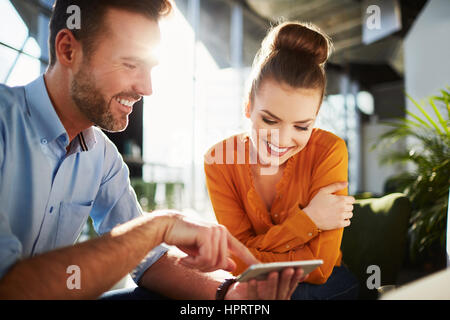 Matura in moderno cafe godendo del tempo insieme telefono di esplorazione Foto Stock