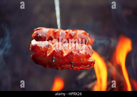 Salsicce oltre l'bondfire in natura - il fuoco selettivo Foto Stock