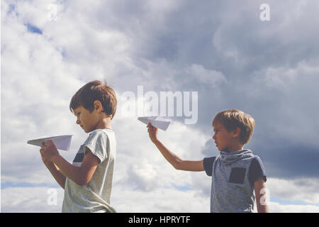 Ragazzi piccoli con piani di carta contro il cielo blu. Basso angolo di visione Foto Stock