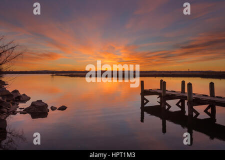 Uno spettacolo di luci nel cielo durante l'ultima alba dell'anno come le nuvole prendere su più colori e riflettere nel fiume Potomac Foto Stock