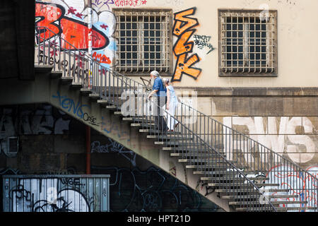 Un giovane va' verso l'alto sulle scale dietro la parete con graffiti. Berlino, Germania. Foto Stock