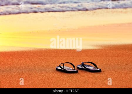 Il flip flop sulla spiaggia al tramonto Foto Stock