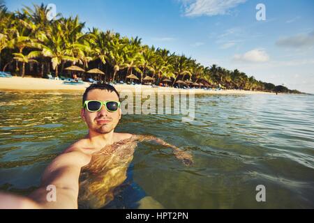 Giovane uomo in vacanza prendendo selfie in mare. Foto Stock