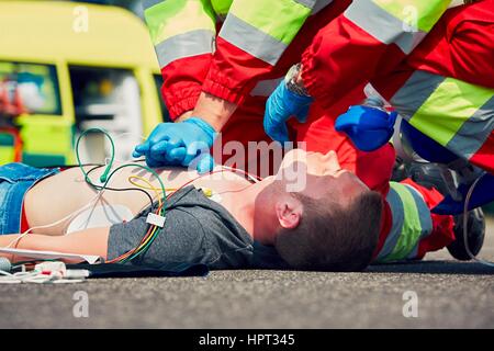 La rianimazione cardiopolmonare. Squadra di salvataggio (medico e paramedico) resuscita l uomo sulla strada. Foto Stock