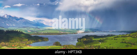 Rainbow e tempesta in montagna con il piccolo lago Foto Stock