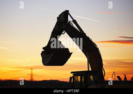 Silhouette del retroescavatore in cantiere Foto Stock