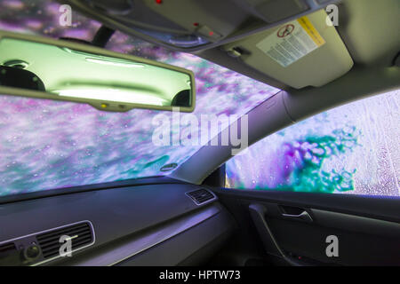 Auto in una stazione di lavaggio automatico sito, schiuma detergente viene spruzzata su, Foto Stock