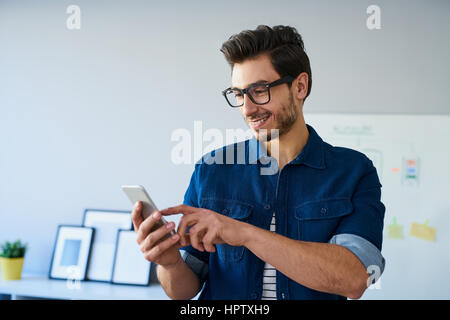 Happy web designer freelance utilizza lo smartphone, lavorando da home office Foto Stock