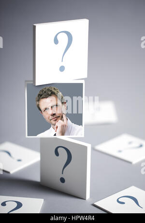 Ritratto di un imprenditore confuso circondato da un punto interrogativo Foto Stock