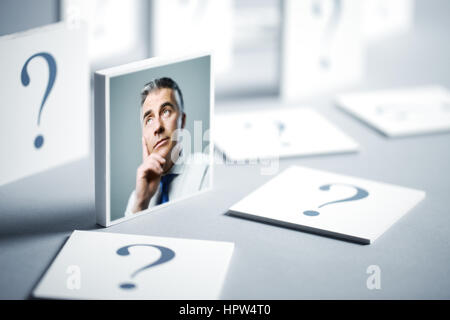 Ritratto di un imprenditore confuso circondato da un punto interrogativo Foto Stock