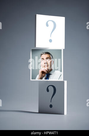 Ritratto di un imprenditore confuso circondato da un punto interrogativo Foto Stock