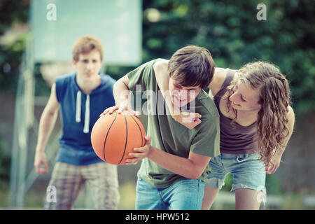 Teens giocando una partita di basket su un tribunale aperto. Foto Stock