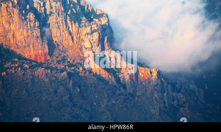 Le nuvole in montagne rocciose al tramonto Foto Stock