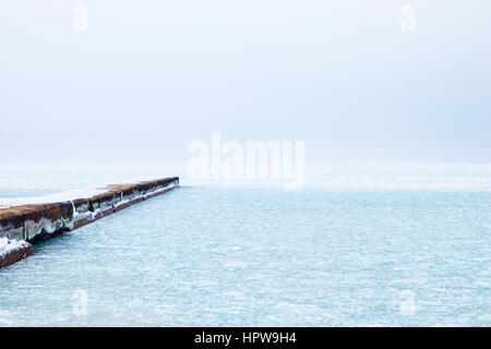 Mare ghiacciato e la neve sul molo di cemento, minimalista seascape in inverno Foto Stock