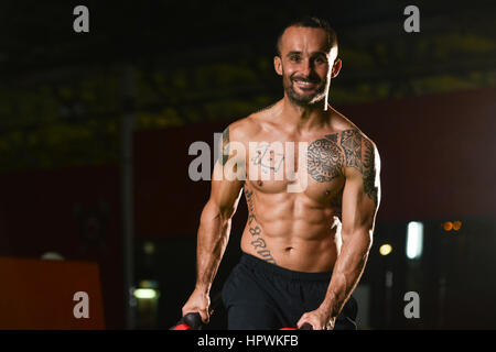 Uomo bello eseguire sacchetto esercizio in ambienti interni in palestra Foto Stock