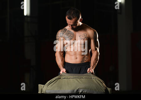 Uomo bello eseguire sacchetto esercizio in ambienti interni in palestra Foto Stock