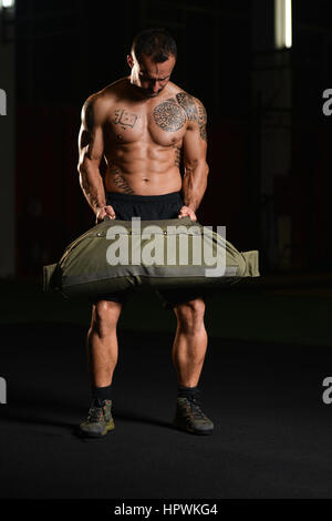 Uomo bello eseguire sacchetto esercizio in ambienti interni in palestra Foto Stock