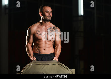 Uomo bello eseguire sacchetto esercizio in ambienti interni in palestra Foto Stock