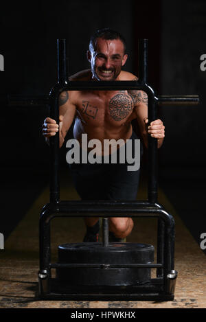 Facendo culturista peso pesante esercizio Sled spingere in palestra Foto Stock