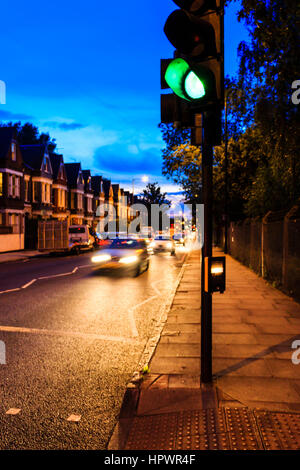 Blu e arancione urban scena notturna con motion-traffico sfocata che si avvicinano ad un semaforo verde in primo piano, Archway Road, London, Regno Unito Foto Stock