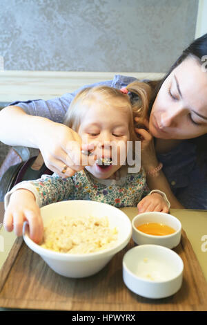 Madre di porridge di alimentazione il suo bambino con una sana prima colazione Foto Stock