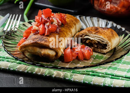 Chimichanga messicano con salsa dip su una piastra Foto Stock