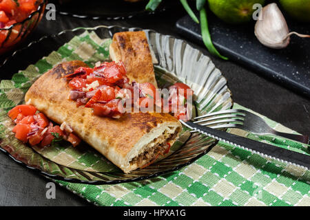 Chimichanga messicano con salsa dip su una piastra Foto Stock