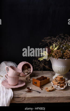 Arrosto di caffè macinato in una scatola di legno con rosa tazze in porcellana e cookie. Vintage vita ancora sul tavolo di legno e copia di spazio. Foto Stock