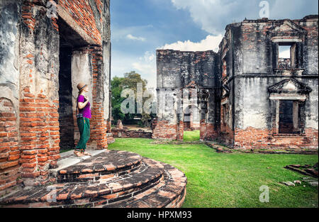 Donna turista con fotocamera foto guardando antichi rovinato Tempio della città di Lopburi, Thailandia Foto Stock