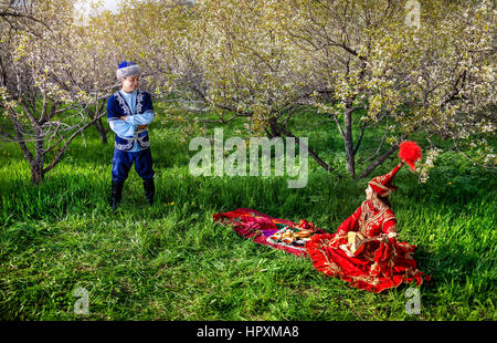 Matura in costume kazako in primavera fiorisce il giardino di Apple a un picnic con dombra ad Almaty in Kazakistan e in Asia centrale Foto Stock