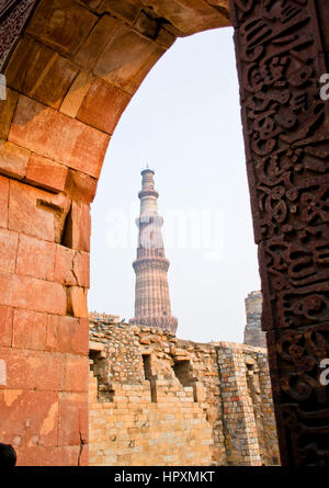 La Qutub Minar minareto, osservata attraverso un arco, in Qutb Minar complesso, Delhi, India Foto Stock