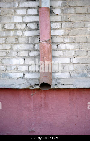 Vecchia grondaia di metallo su un muro di mattoni. Foto Stock