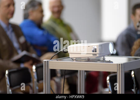 White multimedia proiettore in una sala conferenze con blured persone sullo sfondo Foto Stock