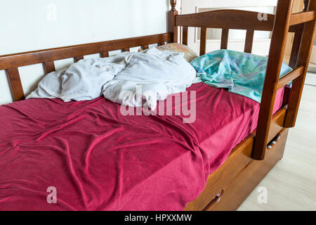 Disfatto letto per bambino con sgualciti di colore rosso e bianco lenzuola e cuscino. Foto Stock